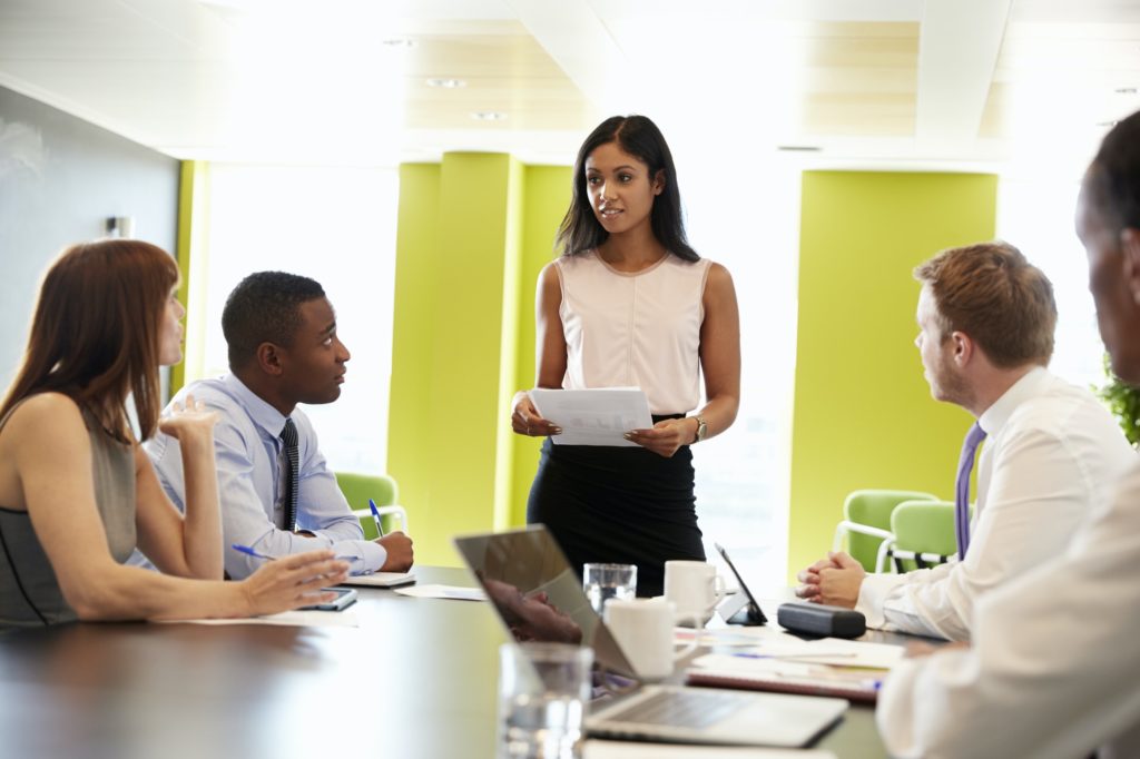 Female boss stands holding document at informal work meeting